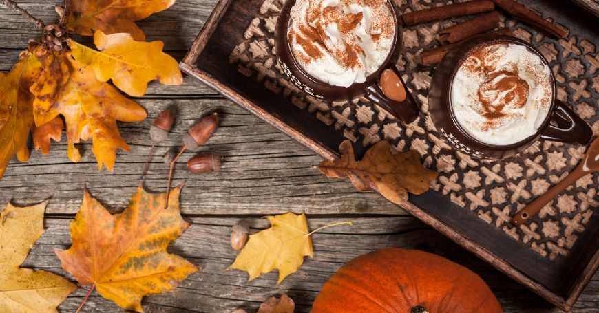tazze di pumkin spice latte circondate da foglie autunnali